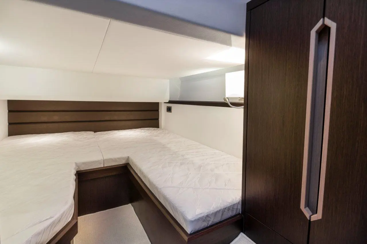 Cozy yacht cabin featuring two twin beds, wooden cabinetry, and soft ambient lighting for a comfortable atmosphere.