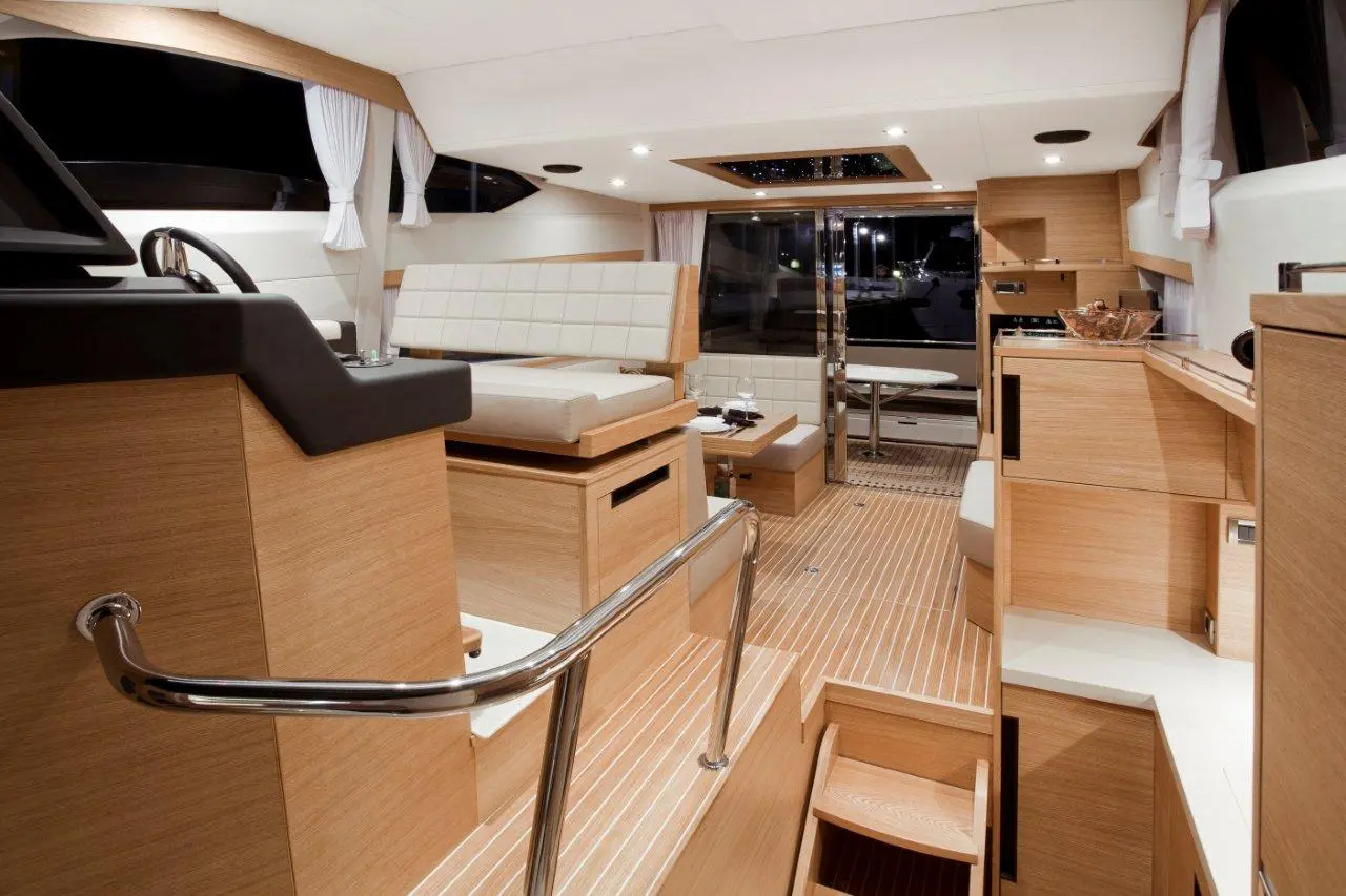 Sleek interior of a contemporary yacht featuring a helm, seating areas, wooden finishes, and stepped access to lower levels.