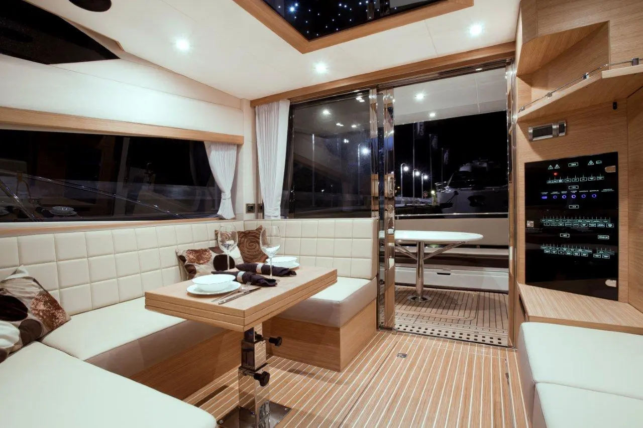 Modern yacht interior featuring a dining area, glass doors, and sleek controls. Soft lighting enhances the elegant atmosphere.