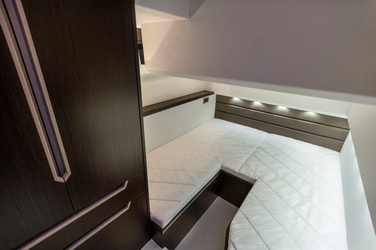 Compact cabin interior featuring twin beds, built-in lighting, and sleek cabinetry, ideal for efficient space utilisation.