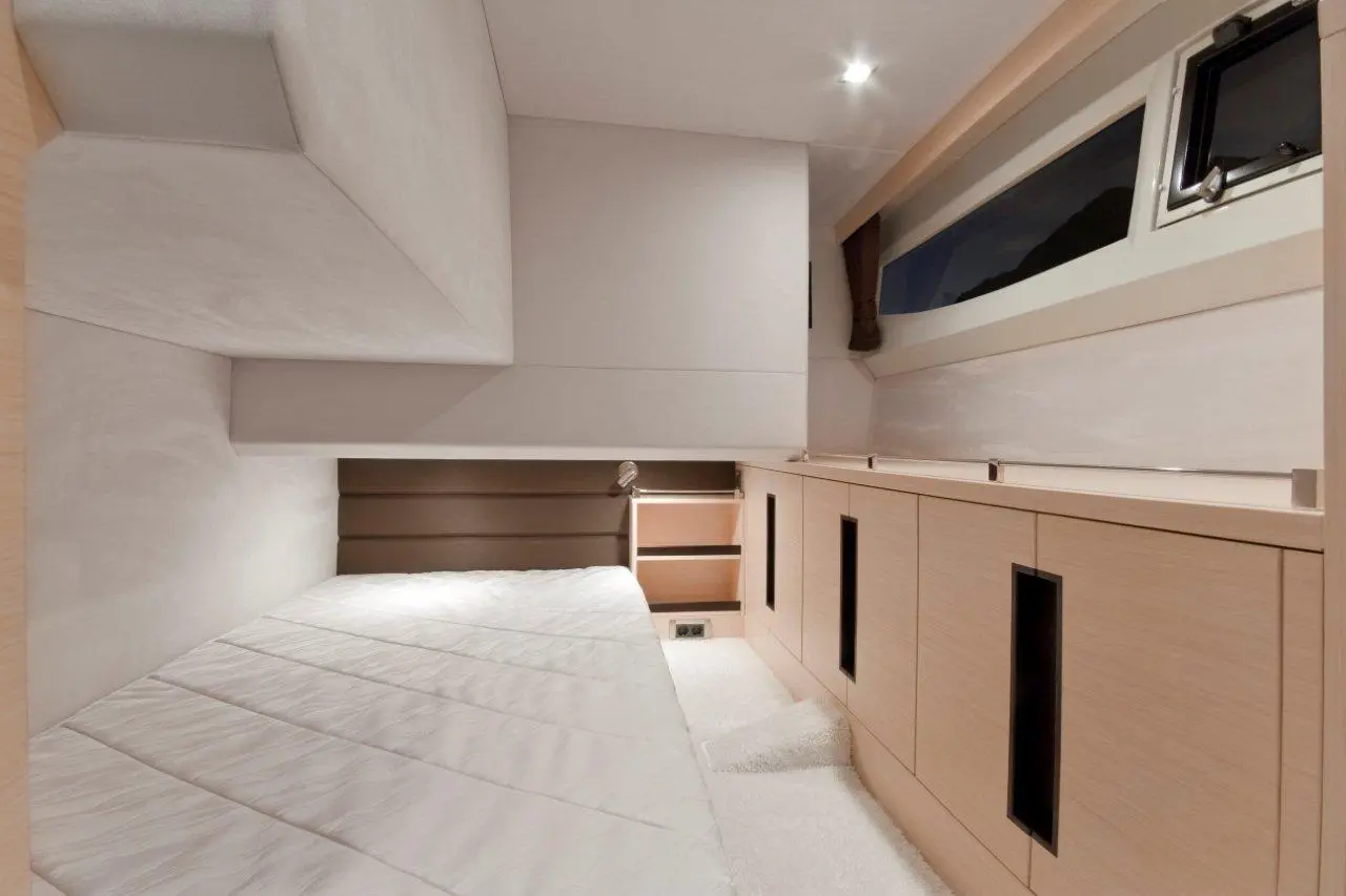 Compact modern bedroom with a white bed, built-in storage, and a window. Warm lighting enhances the minimalist design.