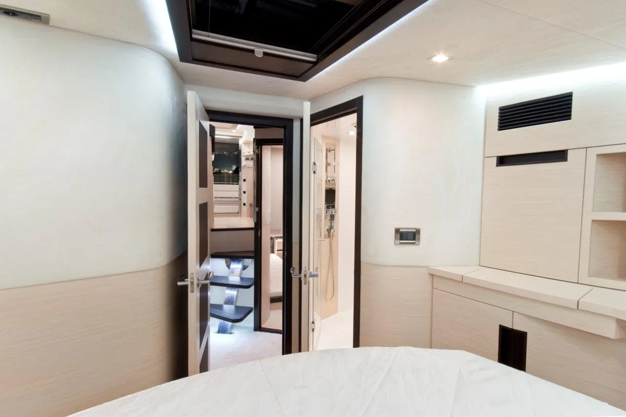 Modern yacht interior showcasing open doors to a bathroom with sleek design, soft lighting, and minimalistic storage solutions.