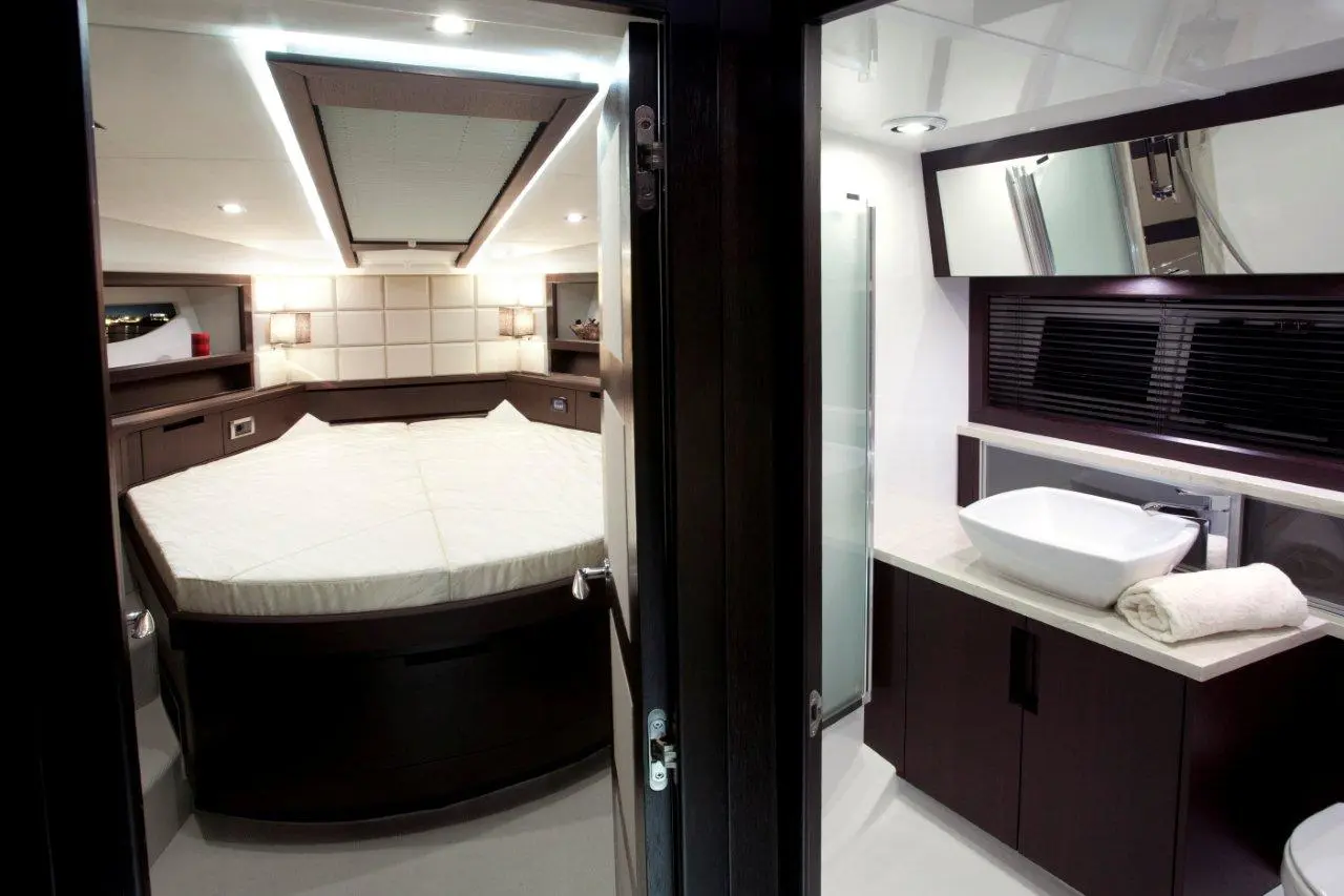 Interior view of a modern boat cabin featuring a round bed, sleek bathroom area, and stylish furnishings with ambient lighting.