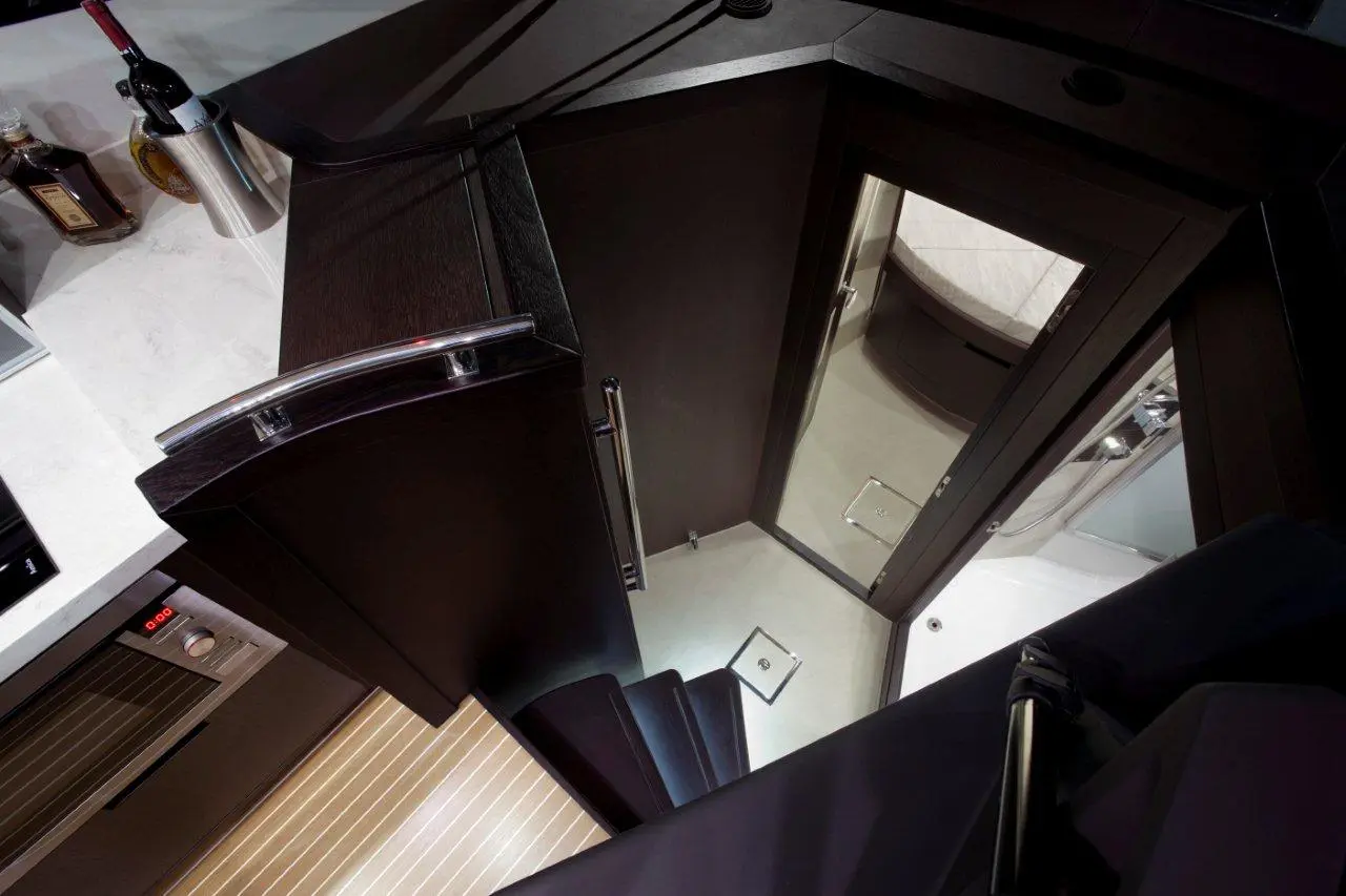 Interior view of a sleek staircase leading to a modern bathroom, with a wine bottle and glassware in the background.