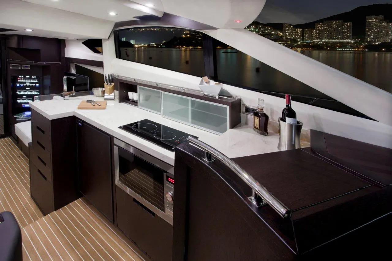 Modern yacht kitchen with sleek cabinetry, marble countertop, induction cooktop, and wine cooler against a city skyline backdrop.