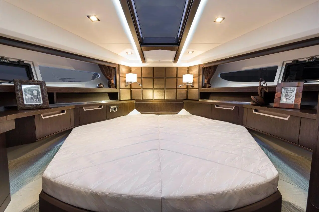 Luxury boat interior featuring a large double bed, wooden decor, storage cabinets, and elegant lamps.