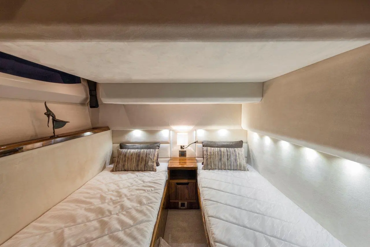 A modern cabin with two single beds, decorative cushions, and soft lighting, showcasing sleek maritime design elements.
