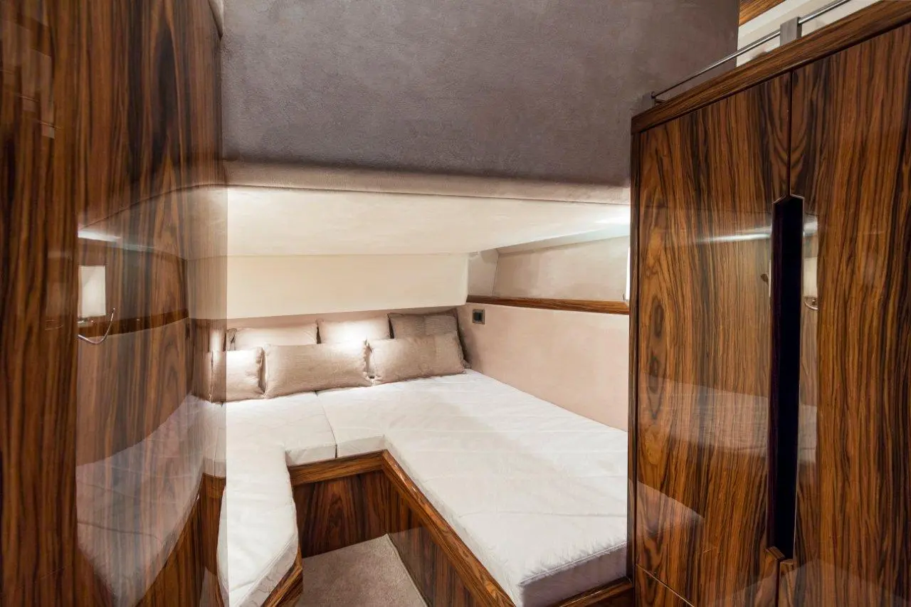 Luxury yacht cabin with twin beds, plush pillows, wooden furnishings, and soft lighting, creating a warm and inviting atmosphere.