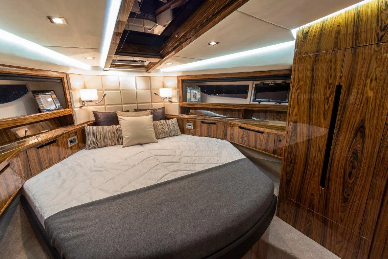 Stylish boat cabin featuring a round bed with cushioned pillows, wooden cabinetry, and soft ambient lighting.