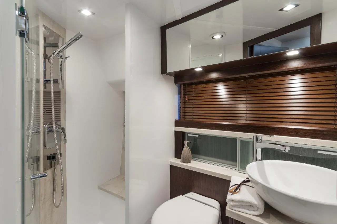 Modern bathroom with a glass shower, wooden accents, a vessel sink, and decorative accessories on a countertop.