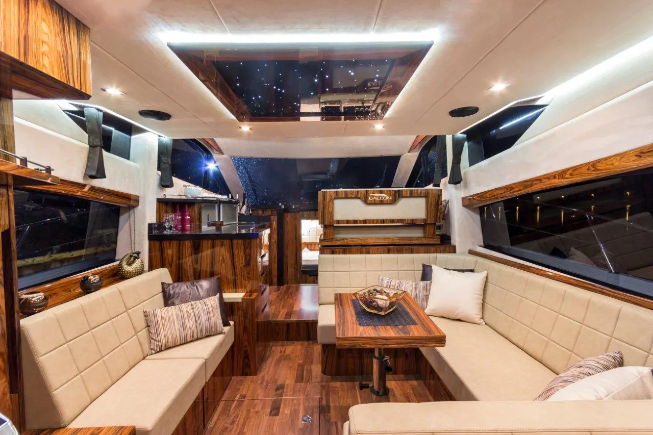 Luxurious yacht interior featuring a stylish seating area, wooden accents, starry ceiling, and modern bar with glass windows.