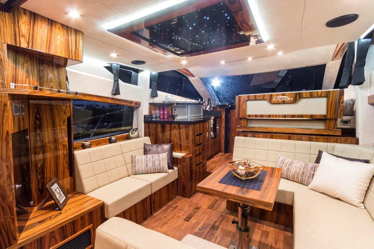 Luxurious boat interior featuring wood finish, plush seating, and modern amenities, highlighted by starry skylights.