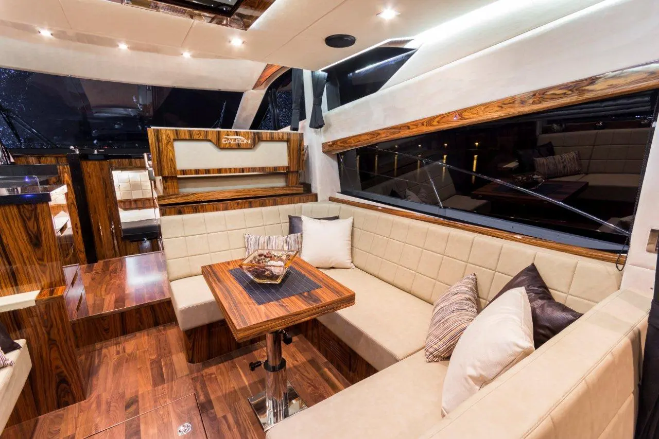 Luxurious yacht interior featuring a wooden table, plush seating, and large windows for scenic views.
