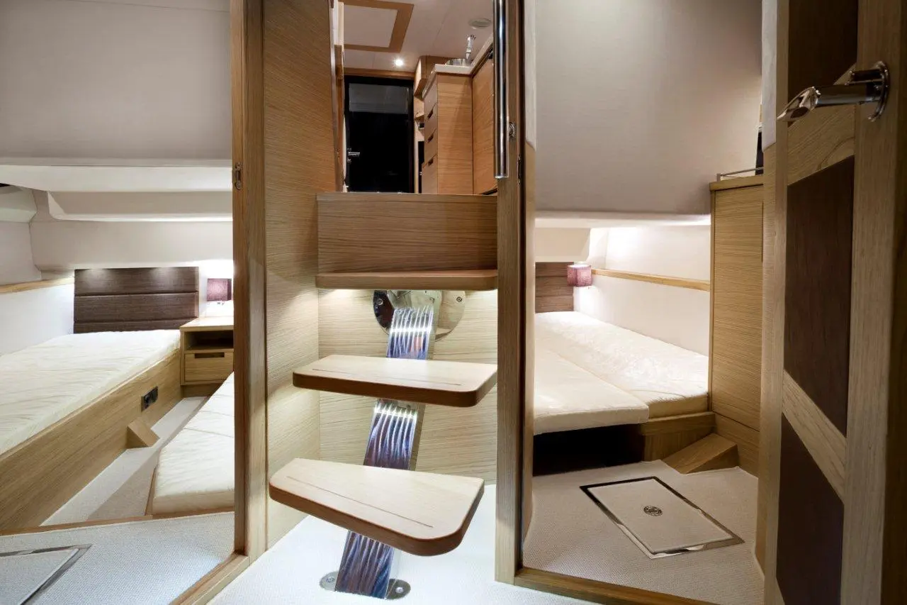 Modern yacht interior featuring wooden steps, soft lighting, and two beds against light walls. Stylish design and spacious layout.