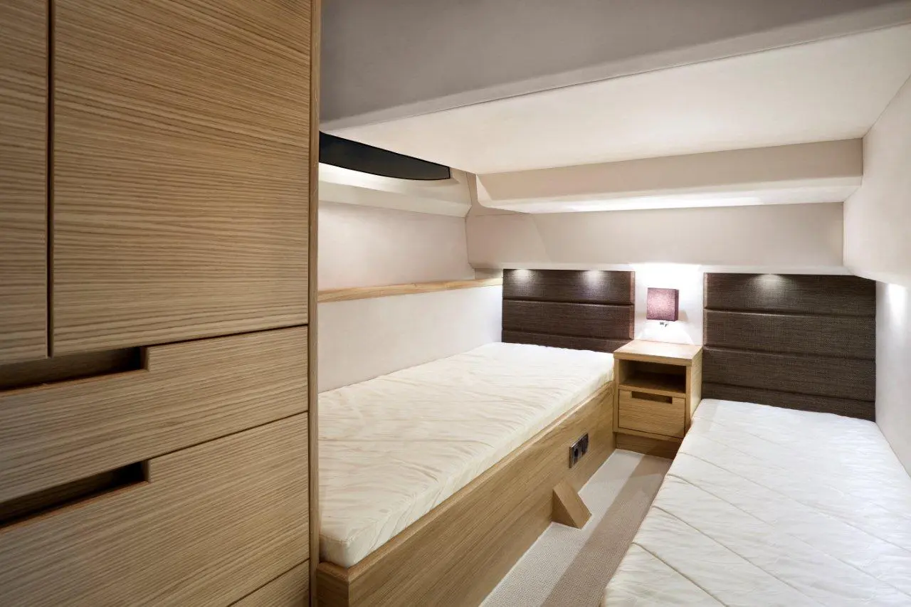 Modern bedroom with two single beds, wooden furniture, and ambient lighting on brown upholstered headboards.