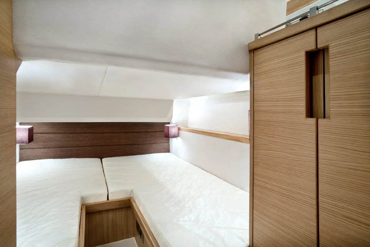 Modern cabin interior with two single beds, wooden storage unit, and soft lighting for a cosy atmosphere.