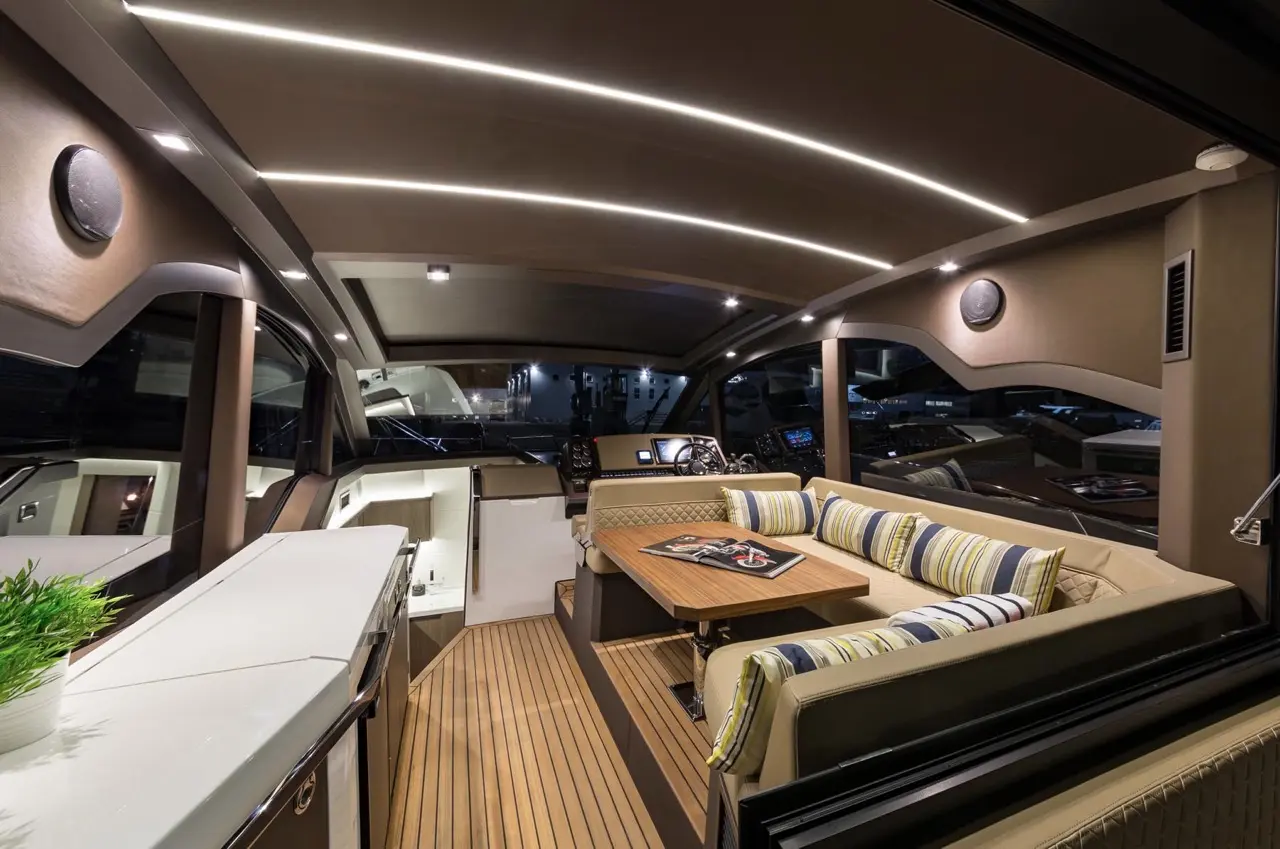 Luxurious yacht interior featuring stylish seating, a wooden table, and modern lighting, with a view of the marina outside.