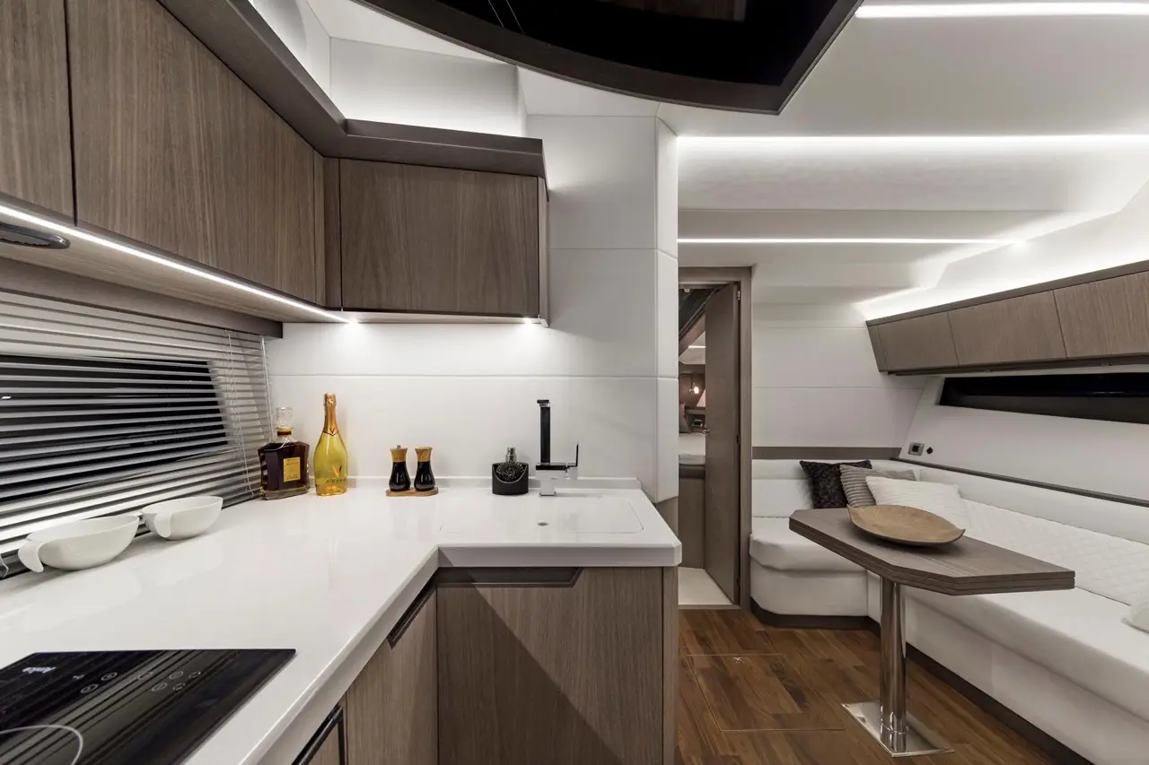 Modern kitchen interior featuring sleek wooden cabinetry, a white countertop, and a cozy seating area with a dining table.