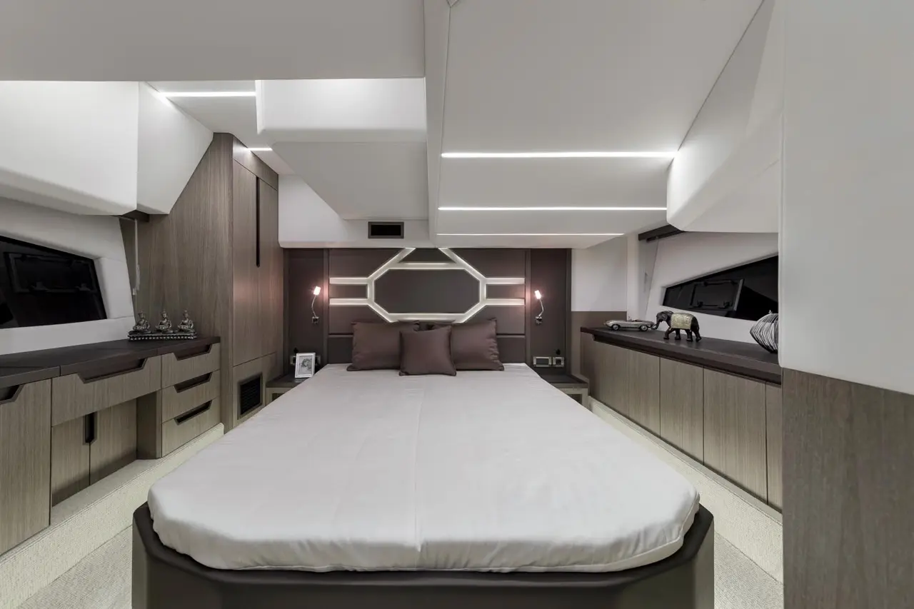 Modern yacht bedroom featuring a double bed with brown pillows, sleek cabinetry, and stylish lighting accents.