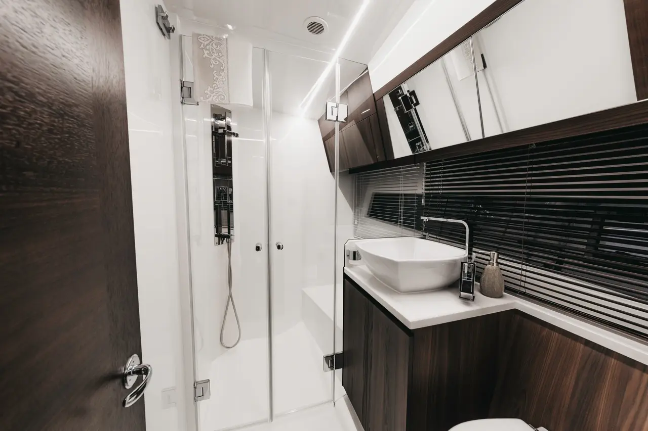 Modern bathroom featuring a glass shower, sleek sink, wooden cabinetry, and stylish decor elements.