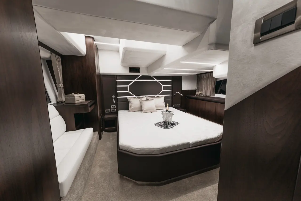 Luxurious yacht bedroom featuring a king-size bed, stylish decor, and a seating area with a champagne bottle on display.