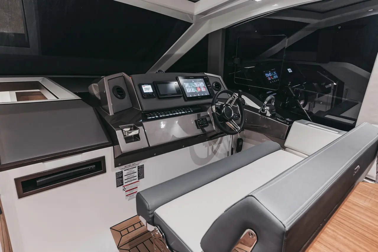 Modern yacht cockpit with sleek controls, digital displays, and comfortable seating, featuring nocturnal lighting ambiance.