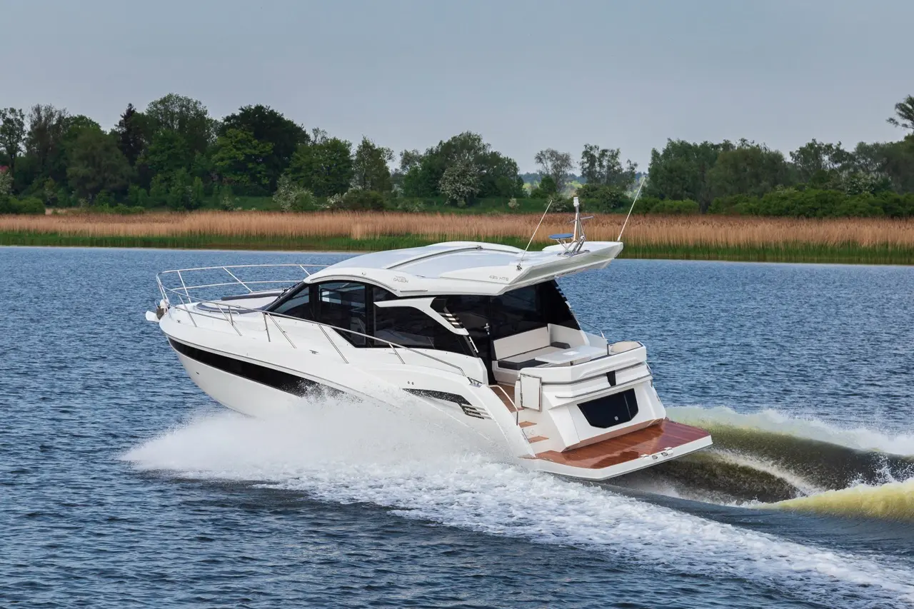 A sleek white motorboat speeds across a calm lake, trailing white waves with lush greenery in the background.