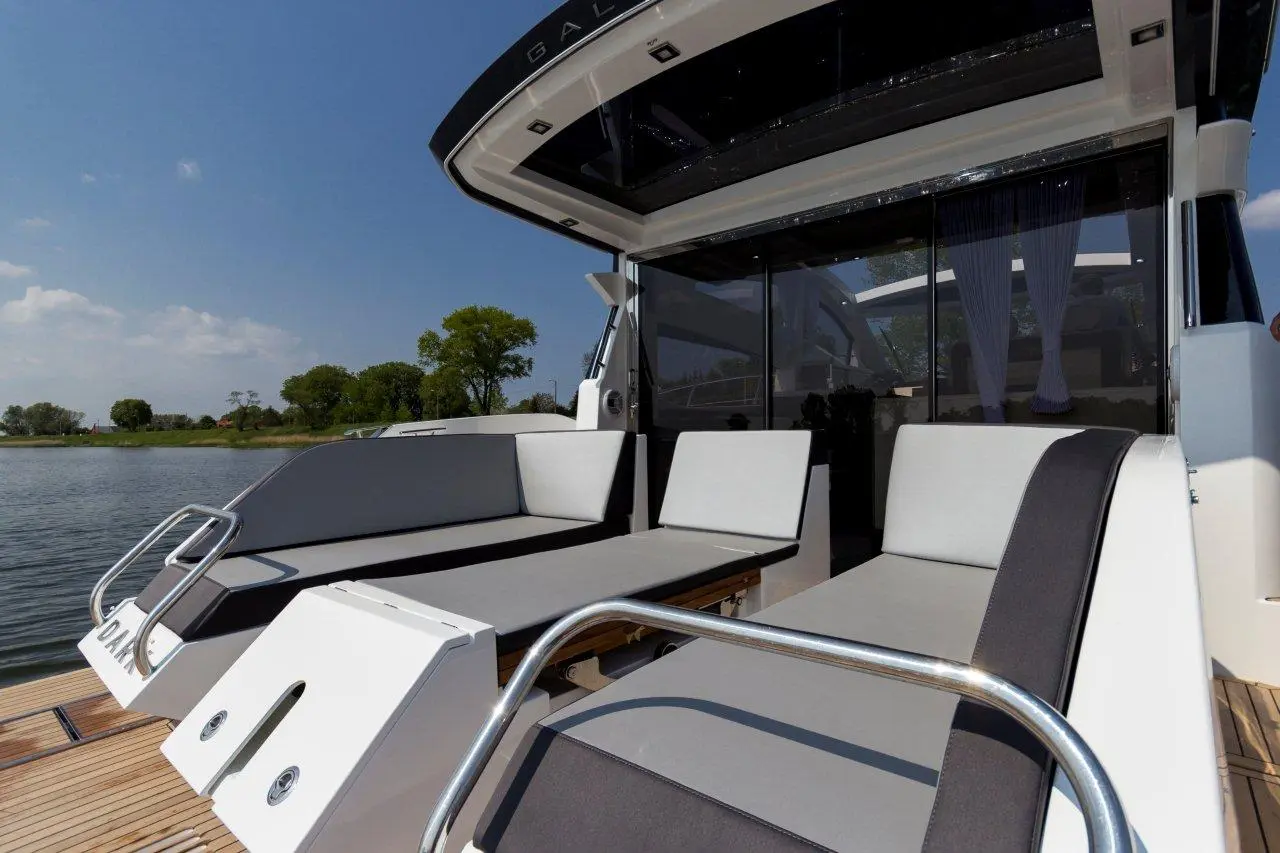 Luxury boat deck with modern seating and panoramic windows overlooking a tranquil lake and lush greenery.