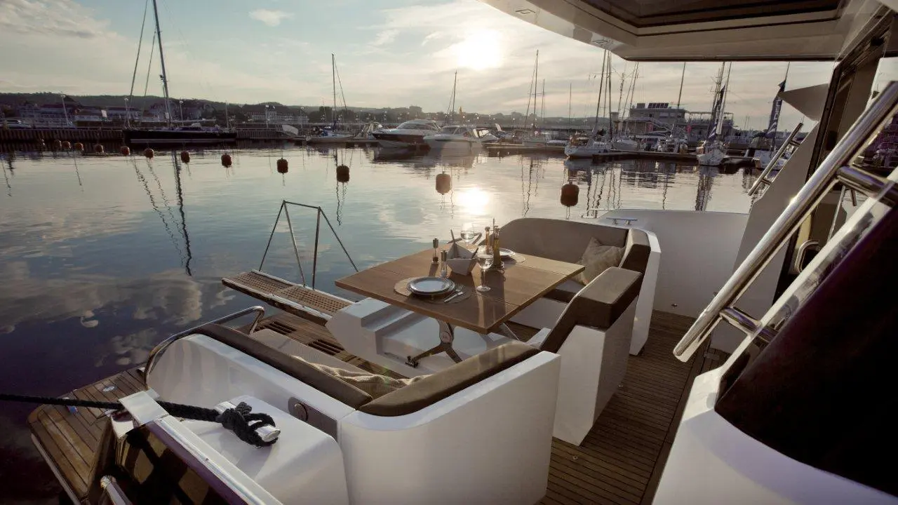 Elegant yacht dining area with a sunset view over a marina, featuring a table set with plates and glasses.