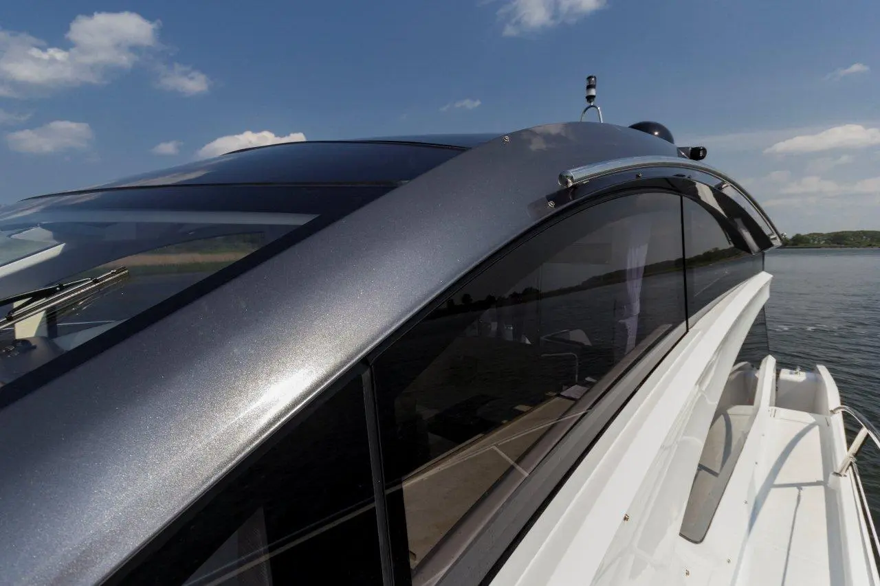 Close-up of a sleek boat's roofline and tinted windows against a blue sky, showcasing clarity and modern design.