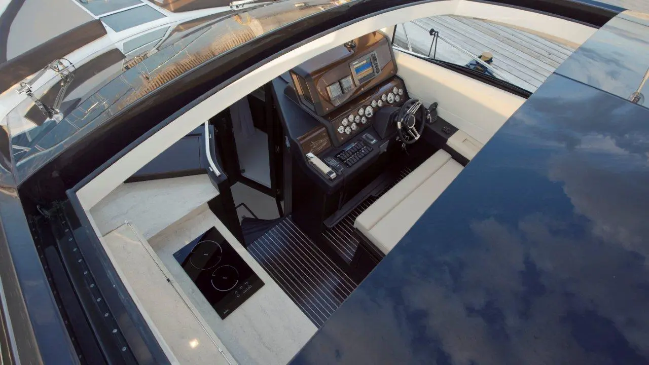 Interior view of a luxury yacht, showcasing a sleek helm with navigation instruments, steering wheel, and seating area.