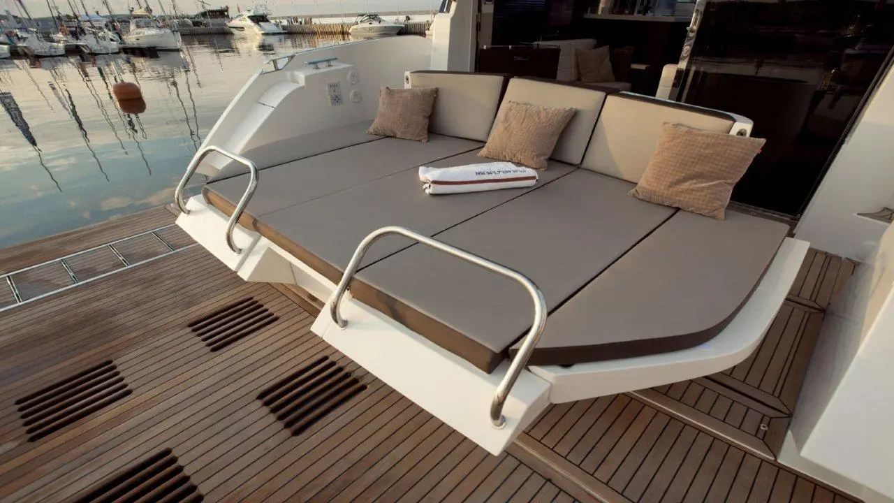 Stylish boat seating area with gray cushions and pillows, overlooking a marina with boats and calm water reflections.