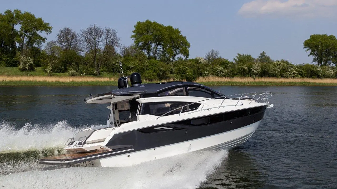 A sleek motorboat gliding over calm water, surrounded by lush greenery and blue skies, showcasing a luxurious design.