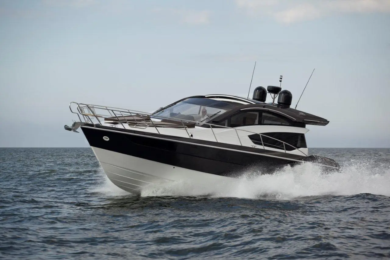 A sleek black and white motorboat cruising through the water, creating splashes and leaving a wake behind.