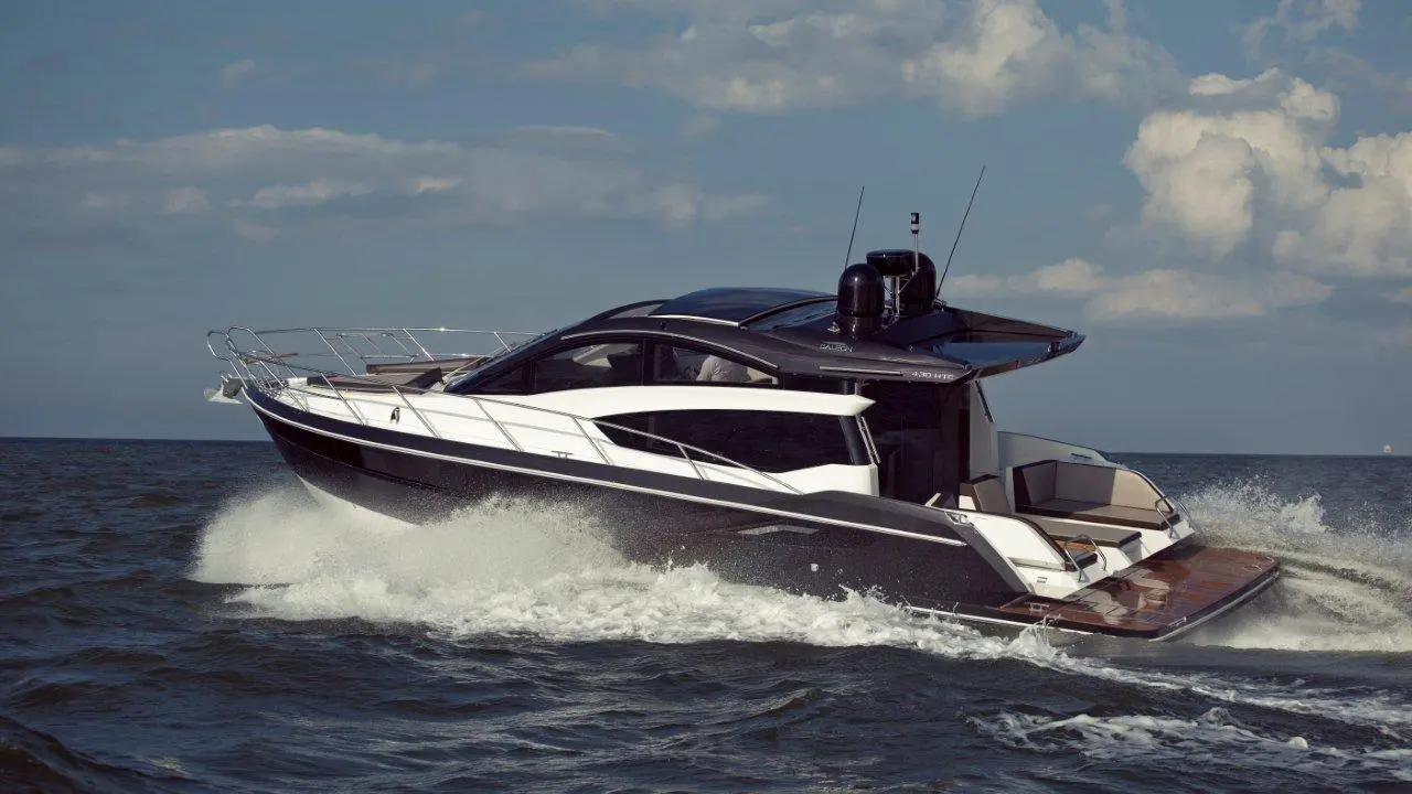 A sleek modern motorboat speeds through the waves under a partly cloudy sky, showcasing its elegant design and luxurious features.