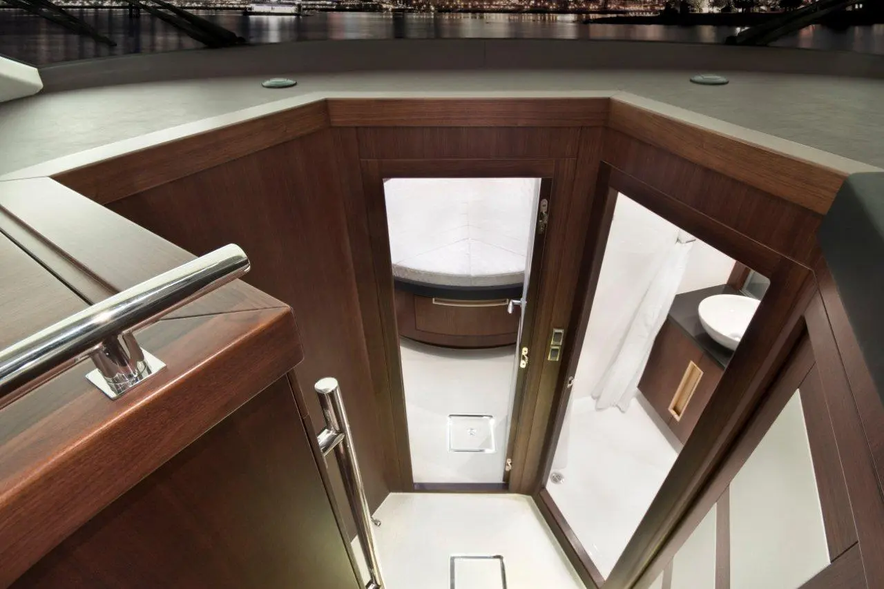 Interior view of a modern boat's bathroom with wooden accents, a shower area, and a circular sink.
