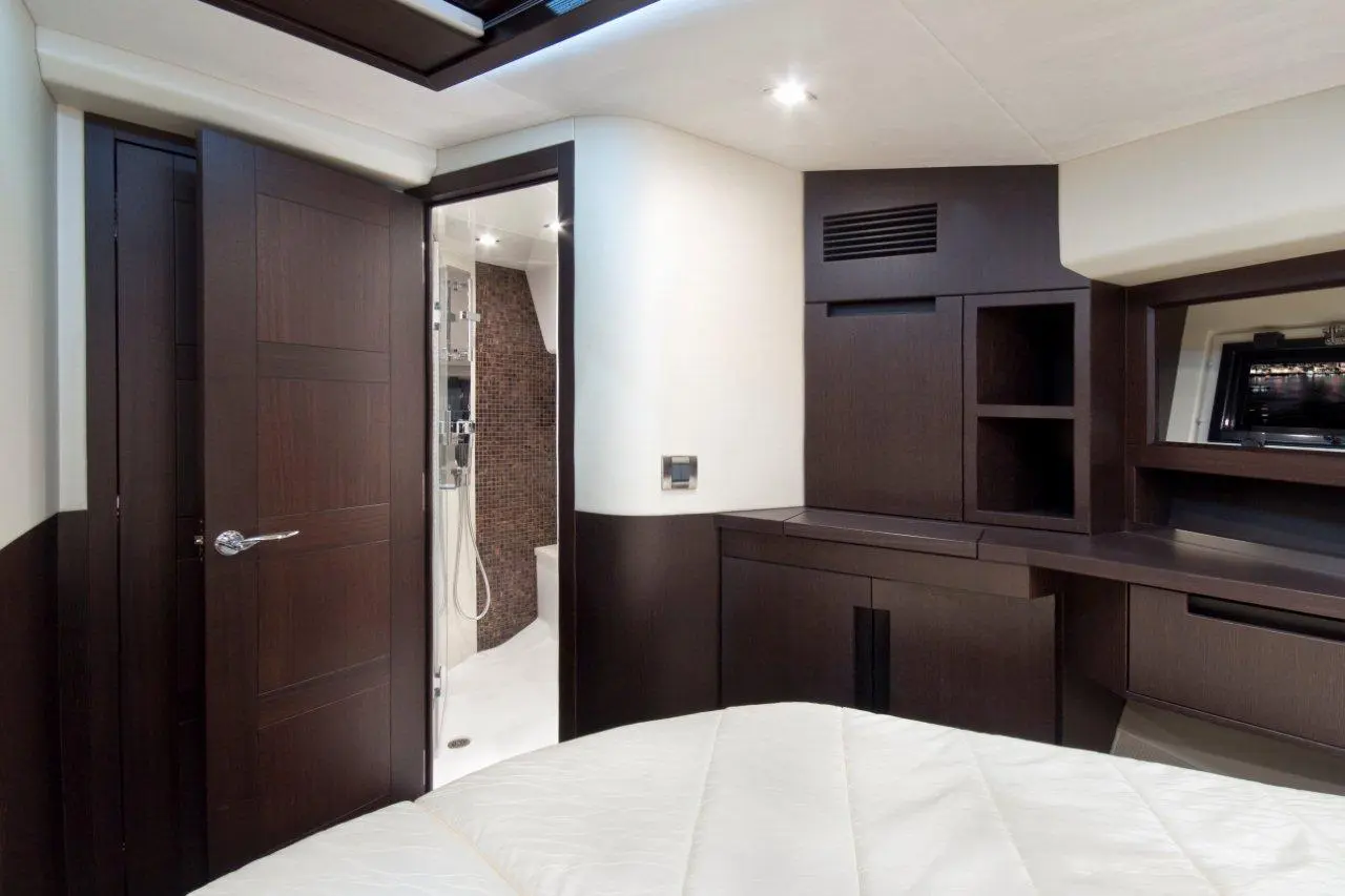 Luxurious yacht interior featuring a bedroom with a bed, dark wood furnishings, and a bathroom visible through a door.
