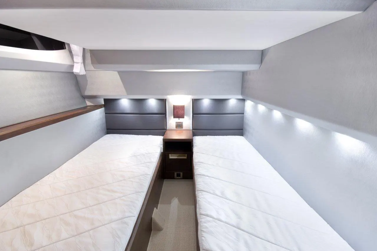 Interior of a modern, minimalistic bedroom featuring twin beds, bedside lighting, and neutral tones, enhancing space utilisation.