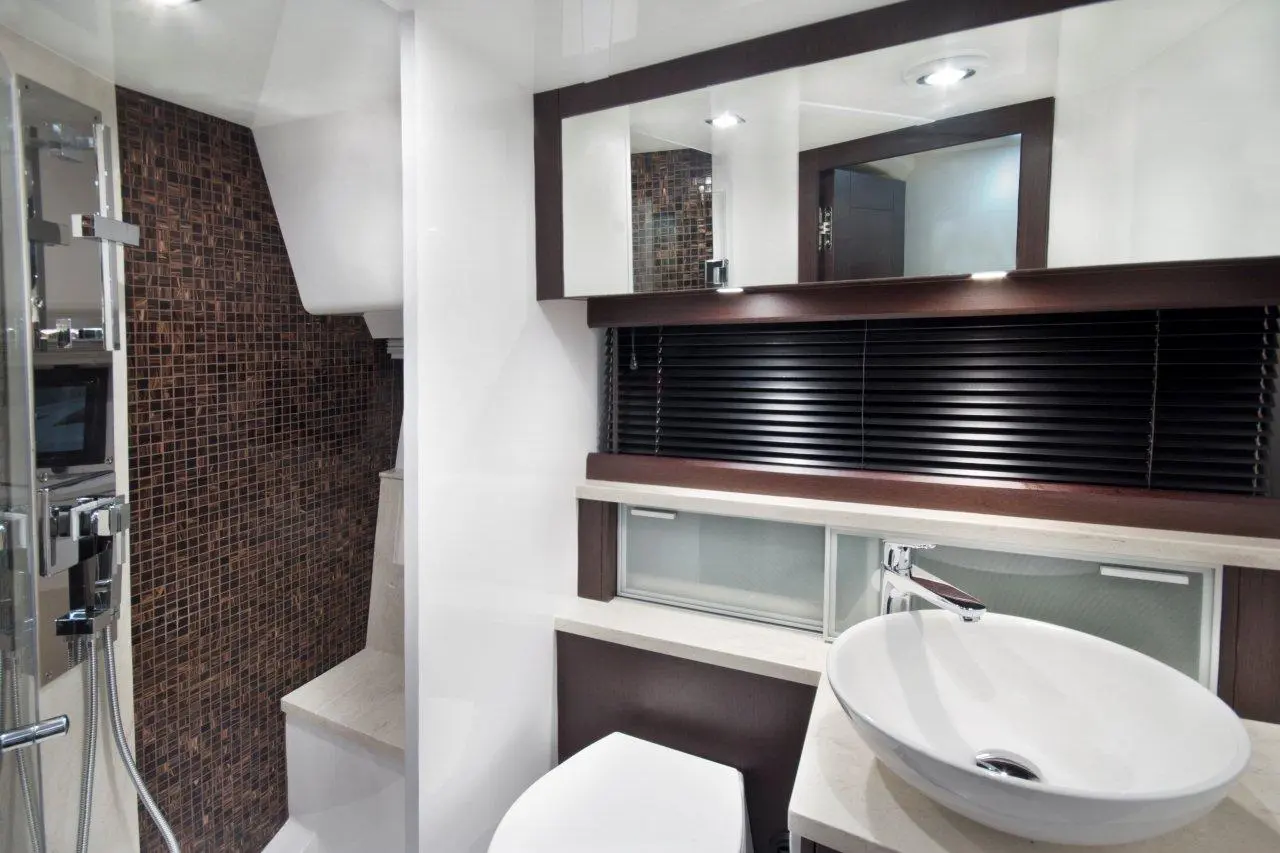 Modern bathroom featuring a sleek design with a round basin, a wall-mounted shower, and textured mosaic tiles.