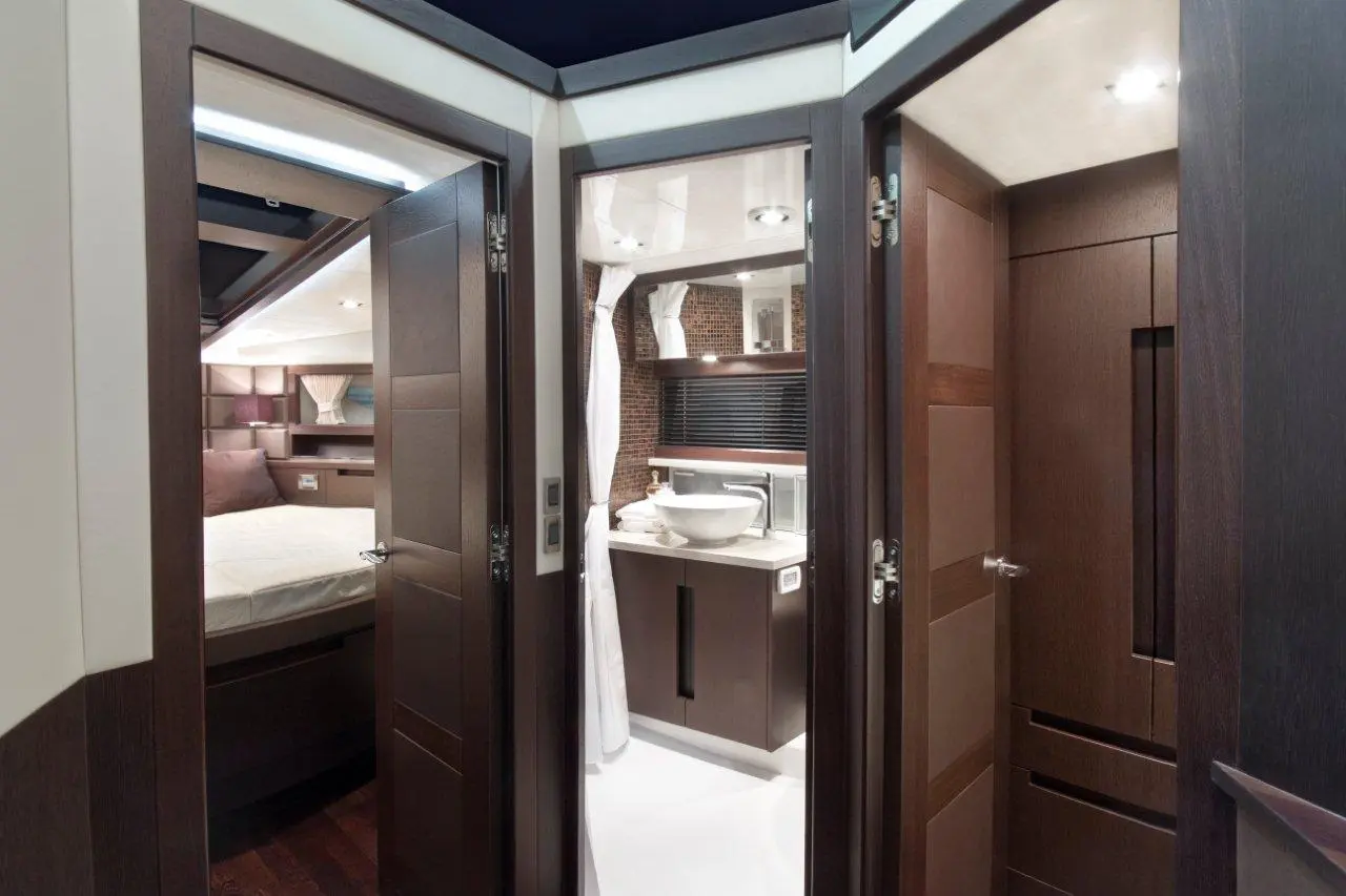 Luxury boat interior showing a doorway leading to a modern bathroom and a cabin with a bed and elegant decor.