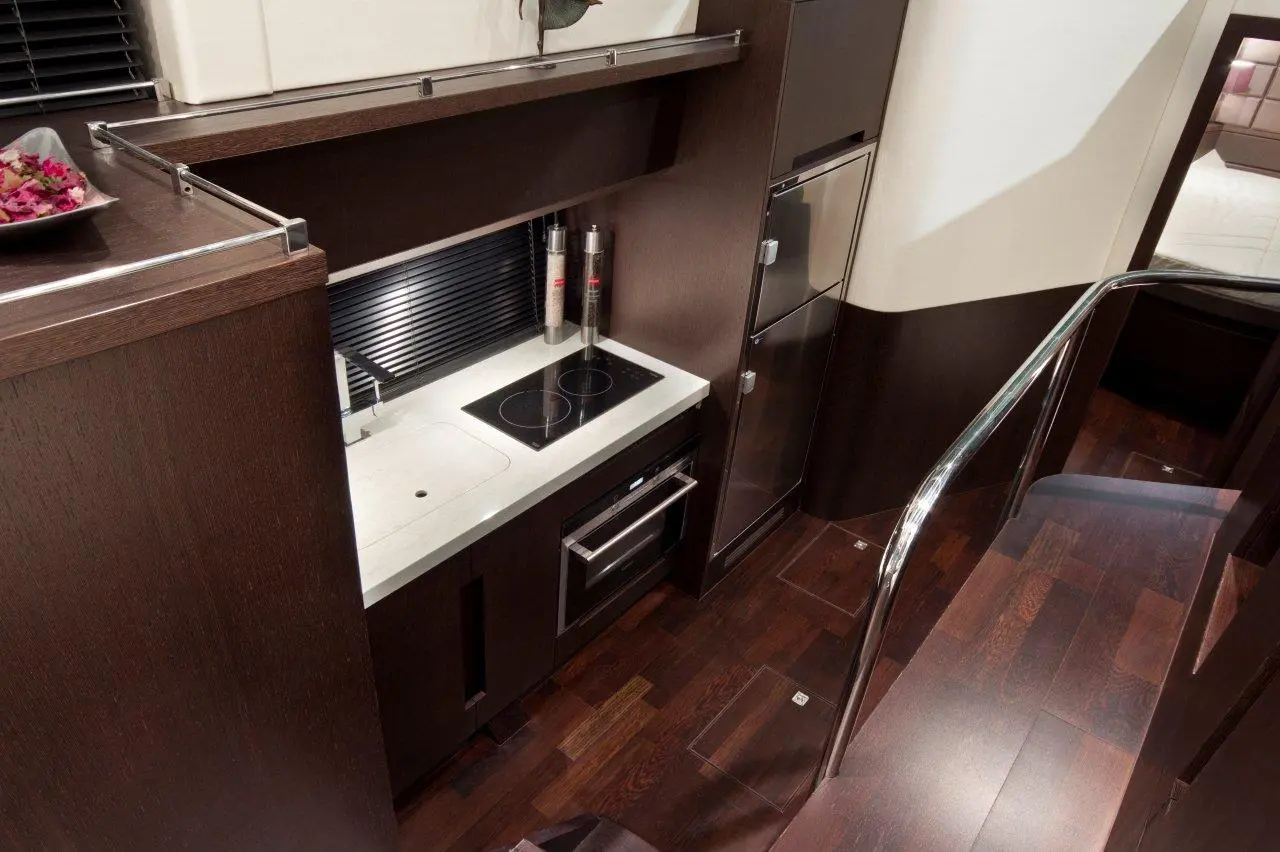 Modern kitchen space with dark wood cabinetry, stainless steel appliances, and a white countertop with an induction cooktop.