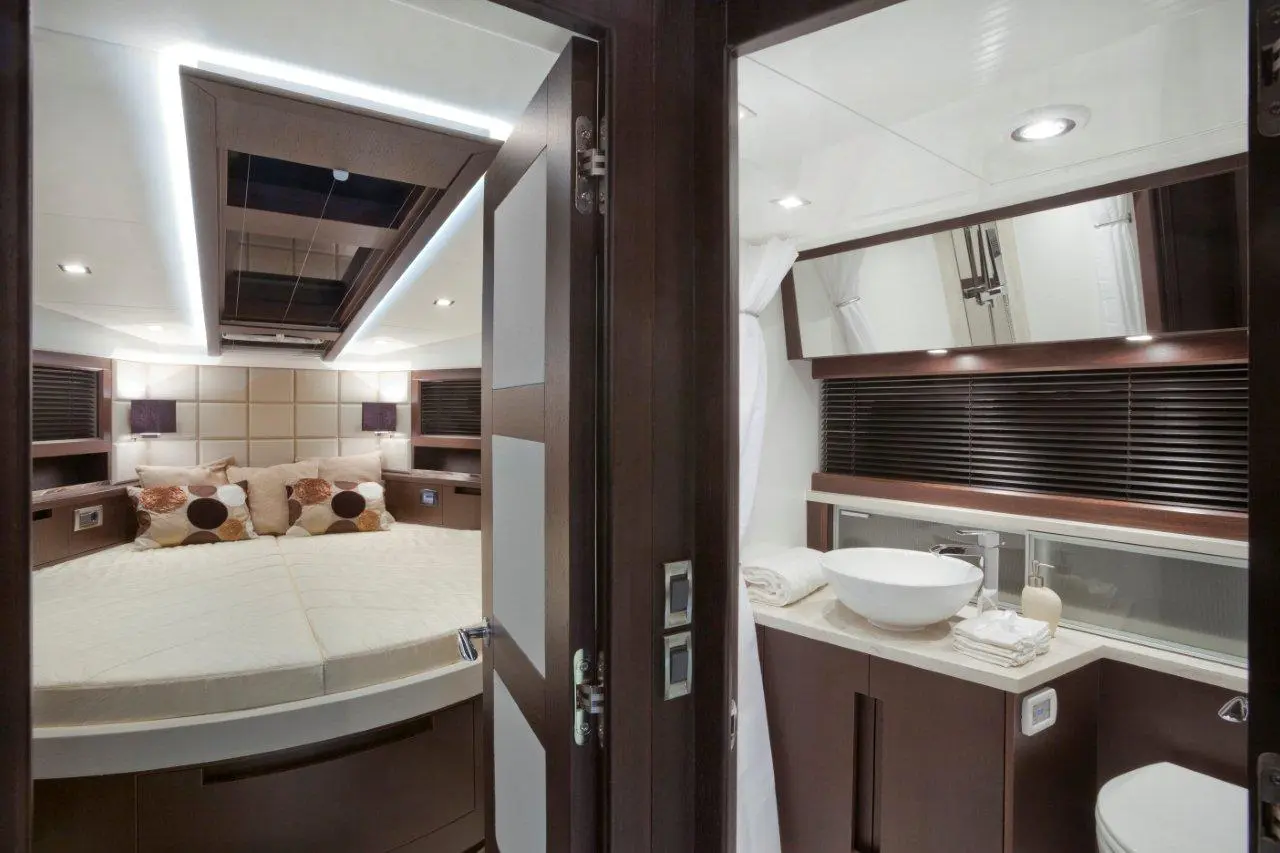 Luxurious boat cabin featuring a queen bed, plush pillows, and an elegant bathroom with a vessel sink and modern decor.