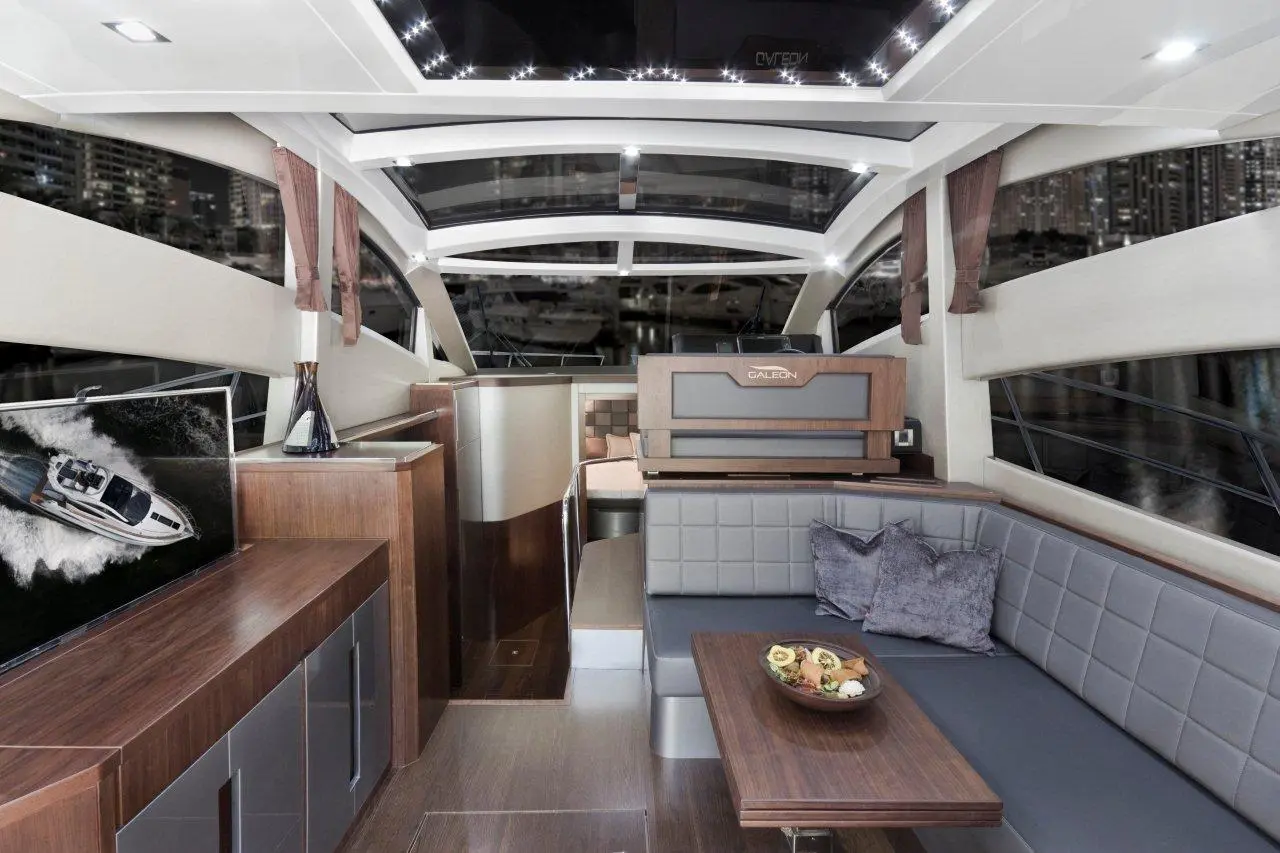 Luxurious yacht interior featuring a lounge area, modern decor, and a table with snacks, overlooking a city skyline.