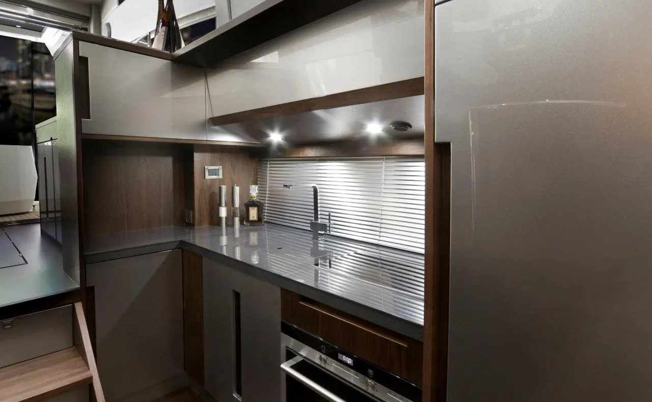 Modern kitchen interior featuring sleek grey countertops, wooden cabinetry, a stylish faucet, and ambient lighting.