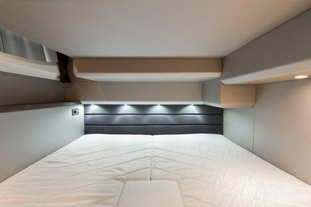 Interior view of a modern sleeping space featuring a mattress, soft lighting, and neutral colour scheme on the walls.