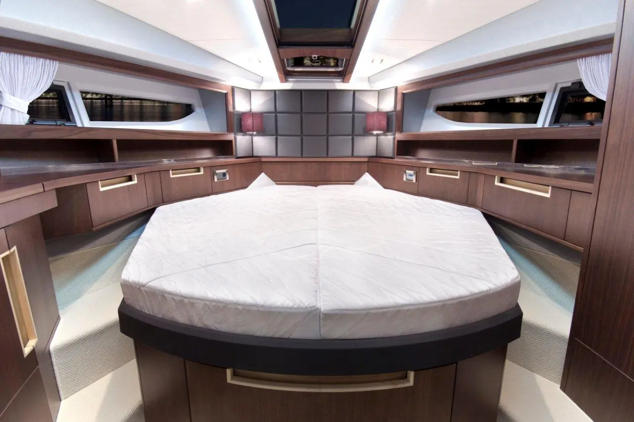 Interior of a luxurious yacht cabin featuring a large circular bed, wooden storage units, and soft lighting.
