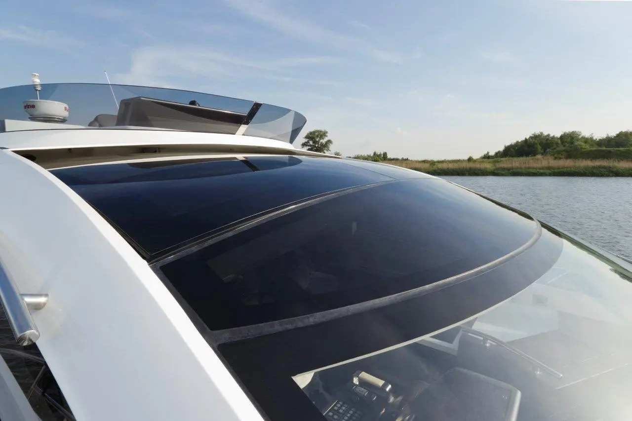 Close-up of a modern boat's cockpit with tinted windows, clear canopy, and waterway visible in the background.