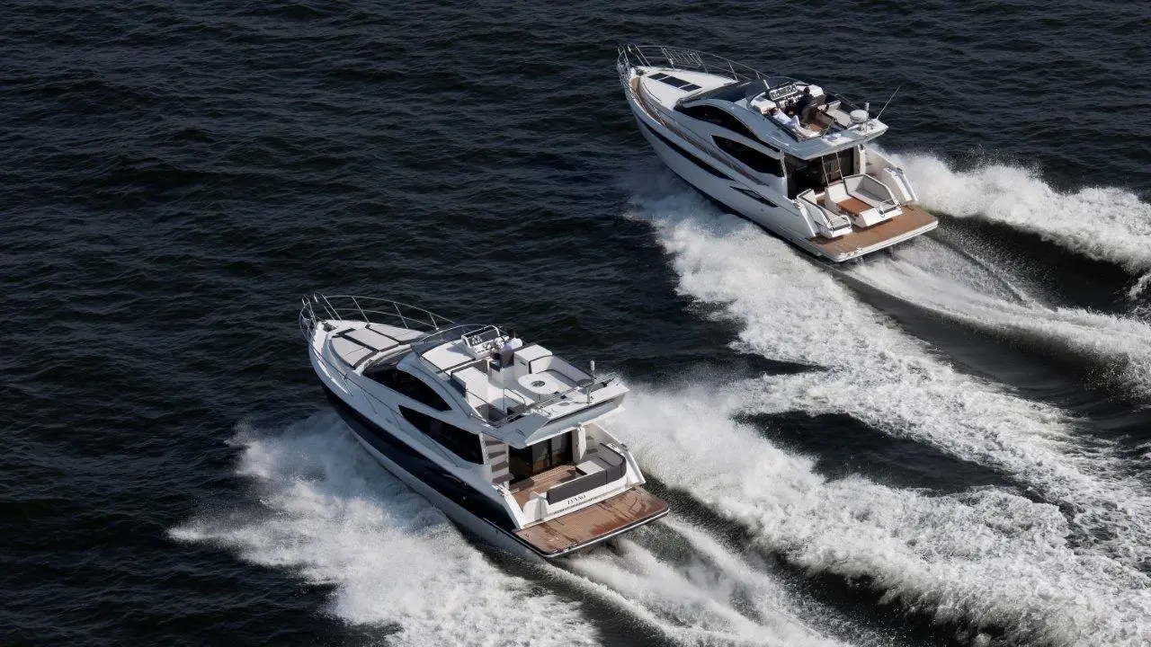 Two luxury motorboats glide through dark blue water, creating white wake trails against the waves.