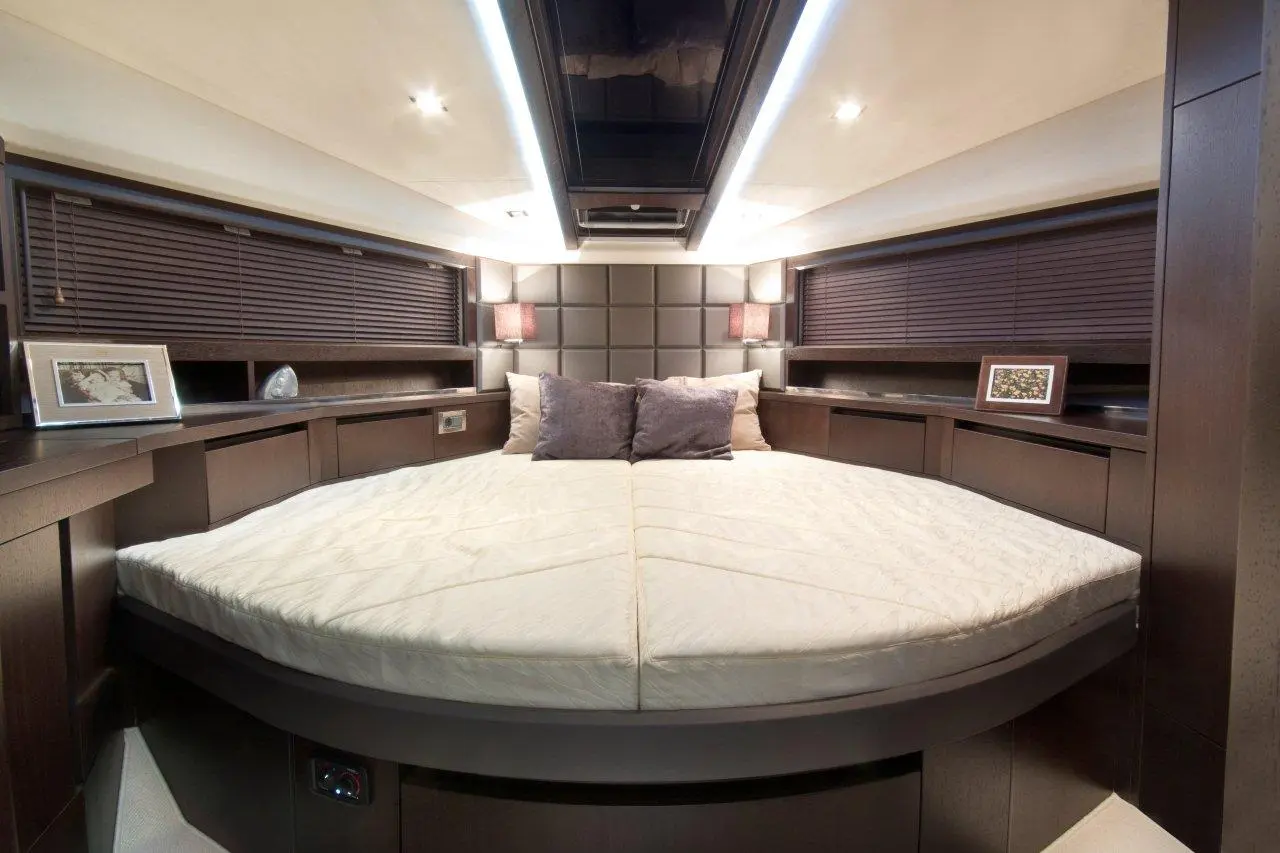 Cozy bedroom with a round bed, soft bedding, decorative pillows, wooden furnishings, and ambient lighting.