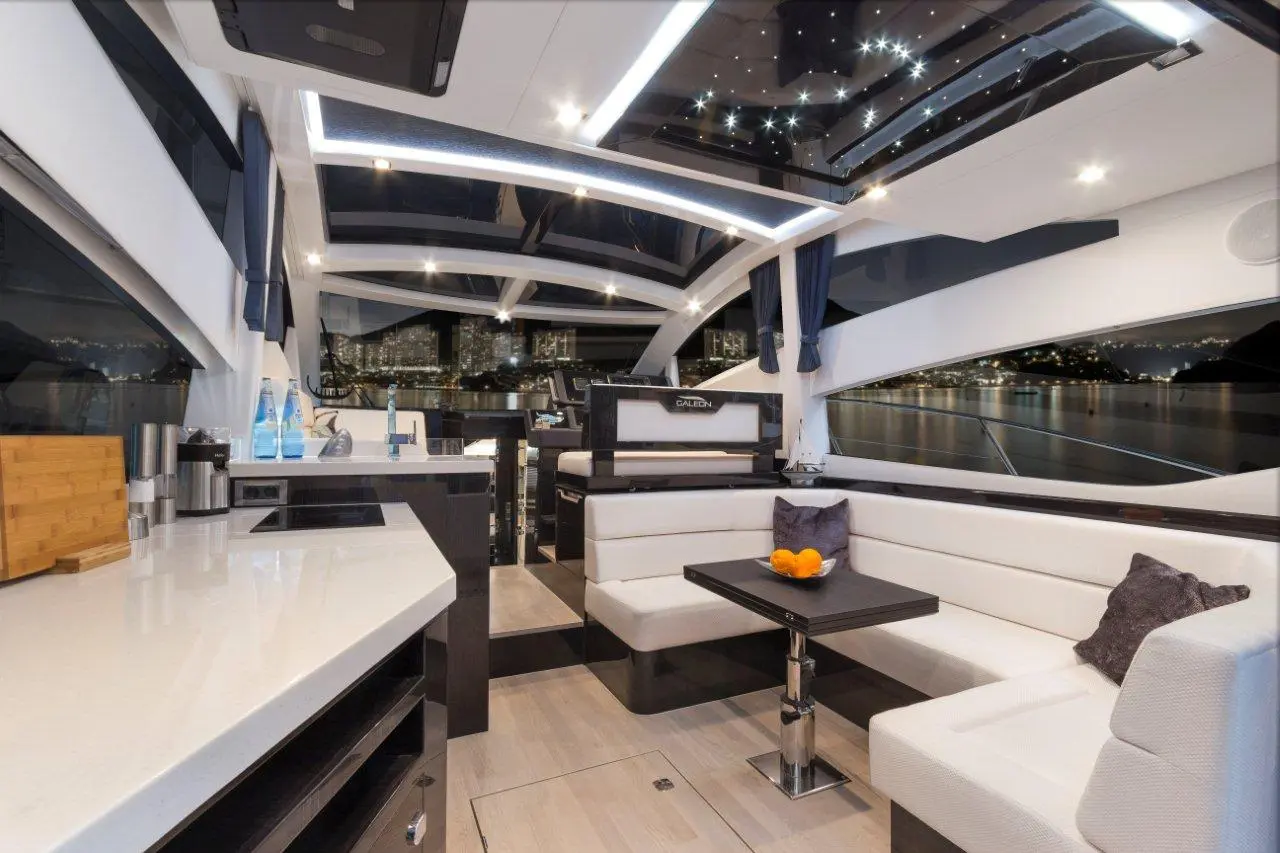 Modern luxury yacht interior with a dining area, starry ceiling, and panoramic views of the night skyline.